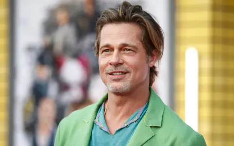 Brad Pitt, attore famoso, sorride con un completo verde acceso.