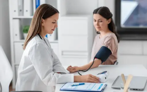 Lekarka mierzy ciśnienie pacjentce. Wynik l4 powyżej 30 dni wymaga dalszej diagnostyki.