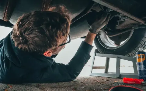 Mechanik bada podwozie auta, szukając objawów awarii elektrozaworu skrzyni biegów.