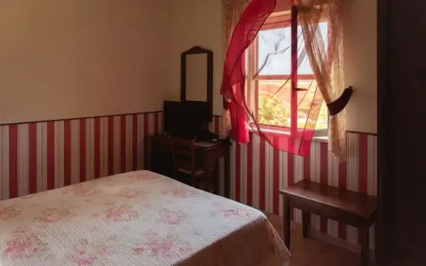 Camera accogliente in un agriturismo a Lamezia Terme, con letto fiorato e tende rosse che danzano al vento.