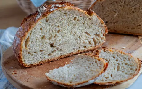 Frisches Brot ohne Sauerteig, mit knuspriger Kruste und luftiger Krume, liegt auf einem Holzbrett.