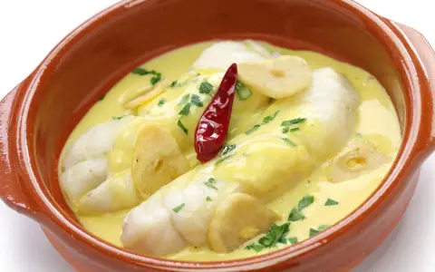 Bacalao al pil pil, uno de los platos típicos vascos, servido en cazuela de barro con ajo y guindilla.