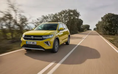 Un coche amarillo Volkswagen T-Cross circula por una carretera rural. ¿Cuánto se tarda en fabricar un coche? ¡Este parece listo para la carretera!