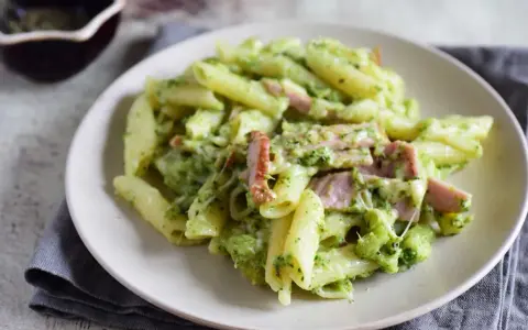 Penne z brokułami i kawałkami szynki w kremowym sosie śmietanowym, posypane serem. Pyszne danie, które zachwyci każdego.
