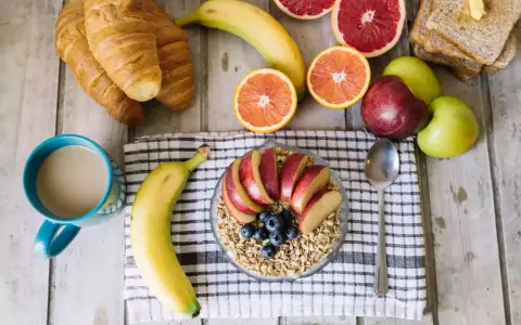 Pyszne i lekkostrawne śniadanie: owsianka z jabłkiem i jagodami, banan, croissanty, cytrusy i kawa.