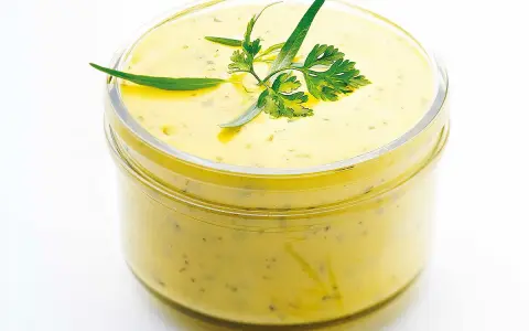 Sauce béarnaise onctueuse dans un bocal, garnie d'herbes fraîches. Parfaite pour accompagner vos plats, cette recette est un délice.