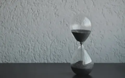 Clessidra con sabbia nera che scorre, simbolo del tempo che passa. Quanto tempo portare il lutto? Il tempo guarisce, ma il ricordo resta.