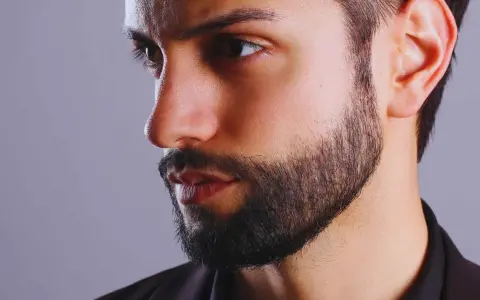 Primer plano de un hombre con barba cuidada, con un estilo fade beard que se difumina hacia las mejillas.