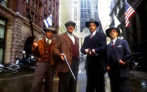 Quatre hommes en costume et chapeau, armés, se tiennent dans une rue de Chicago. Une scène tirée de "Les Incorruptibles, histoire vraie".