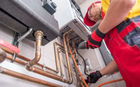 Instalator pracuje przy kotle gazowym, przygotowując go do zmiany właściciela. Dowiedz się, jak przepisać gaz na nowego właściciela PGNiG.