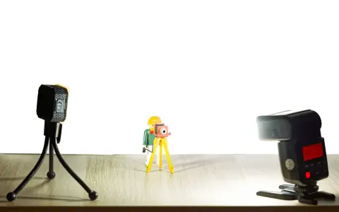 Une figurine Playmobil prend une photo avec un appareil sur trépied. Une autre caméra et un flash sont présents. Vue macro.
