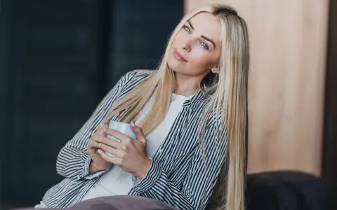 Blondynka z kubkiem w dłoniach, zamyślona, chce być sama.