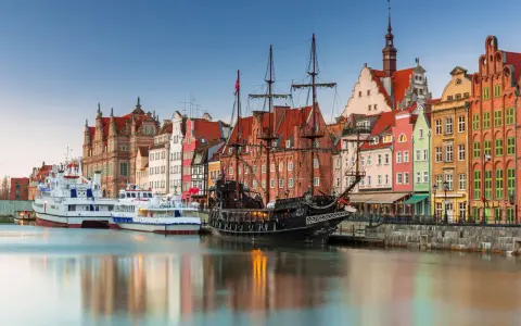 Gdański port z żaglowcem i kolorowymi kamienicami. To miejsce, co warto zwiedzić w Polsce, zachwyca historią i widokami.