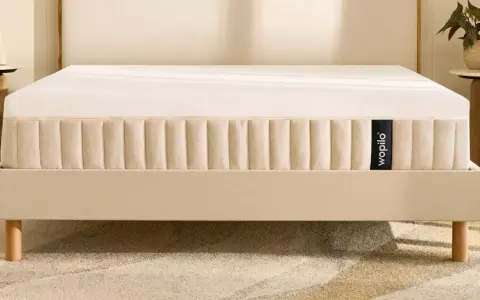 Un matelas hybride Wopilo sur un sommier beige aux pieds en bois. Quel sommier pour matelas hybride ? Ce lit offre un confort optimal.