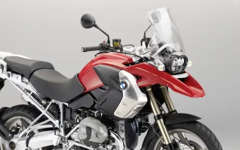 Czerwony motocykl BMW R1200GS z czarnym siedzeniem i dużą szybą.