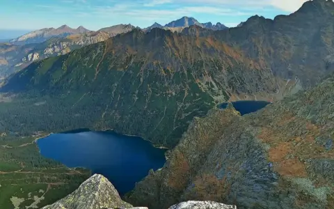 Widok na Tatry z góry. Na pierwszym planie skały, w dole las i jezioro Morskie Oko.