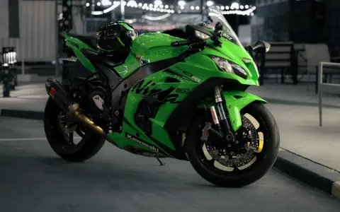 Japoński motocykl Kawasaki Ninja ZX-10R w jaskrawym zielonym kolorze, z kaskiem na siedzeniu, gotowy do nocnej jazdy.