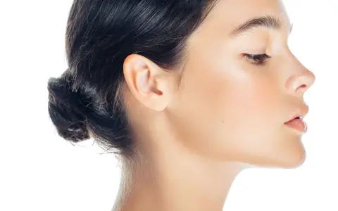 Profilo di donna con trucco leggero, evidenziato il contouring naso per un effetto scolpito. Pelle luminosa e capelli raccolti.