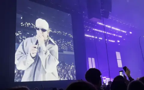 Sobel na ekranie, tłum z telefonami tworzy fiołkowe pole świateł. Koncert w fioletowej poświacie.