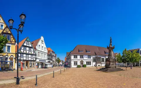 Blick über den Marktplatz der horn-bad meinberg altstadt mit Fachwerkhäusern, einem Denkmal und blauem Himmel.