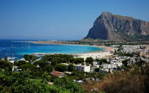 Vista panoramica di San Vito Lo Capo, con la spiaggia affollata e il Monte Monaco. La distanza da Cefalù è di circa 100 km.