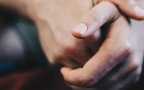 Dita intrecciate, un primo piano che evoca il senso di vibrazione interna e le sue cause, forse ansia o attesa.