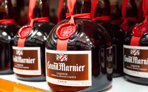 Butelki likieru Grand Marnier, idealnego do margarity. Czerwona wstążka i pieczęć dodają elegancji.