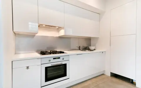 Cuisine moderne blanche avec hotte intégrée au-dessus de la plaque de cuisson. La hauteur de la hotte cuisine est idéale pour une utilisation confortable.