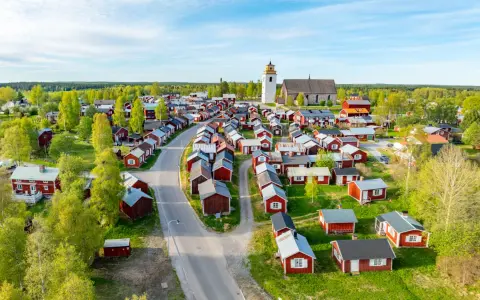 Kyrkstaden Luleå, en idyllisk by med röda hus och en kyrka, badar i solljus.