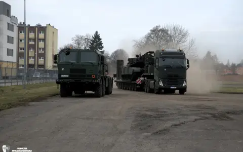 Dwa wojskowe pojazdy, w tym potężny Volvo FH16, transportują ciężki sprzęt.