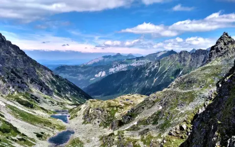 Majestatyczne Tatry Wysokie z doliną, dwoma stawami i skalistymi szczytami pod błękitnym niebem.