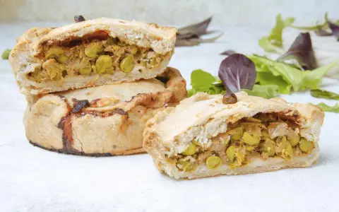 Panades mallorquinas cortadas, mostrando el relleno de guisantes y carne.