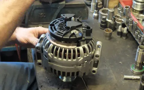 Warsztat samochodowy. Mechanik pracuje nad regeneracją alternatora. Sprawdź, jaka jest regeneracja alternatora cena.