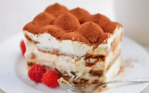 Pyszne tiramisu bez jajek Magdy Gessler, udekorowane malinami i kakao, czeka na widelczyk.