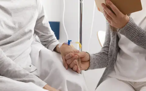 Dwie osoby trzymają się za ręce. Jedna z nich ma założony wenflon. Czy lewatywa jest zdrowa? To pytanie, na które odpowiedź zależy od kontekstu medycznego.