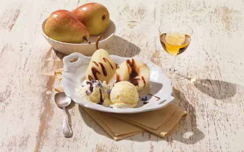 Gegarte Birnen mit Schokoladensauce und cremigem Vanilleeis, garniert mit Lavendelblüten. Ein köstliches Birnen Eis Dessert.