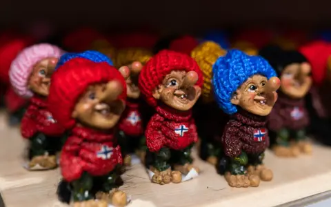 Uśmiechnięte trolle norweskie w kolorowych czapkach i sweterkach z norweską flagą.