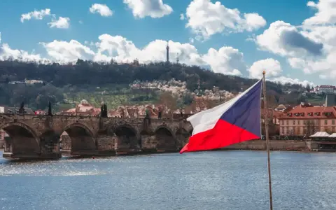 Flaga Czech na tle Mostu Karola w Pradze. Zastanawiasz się, ile idzie paczka z Czech do Polski?