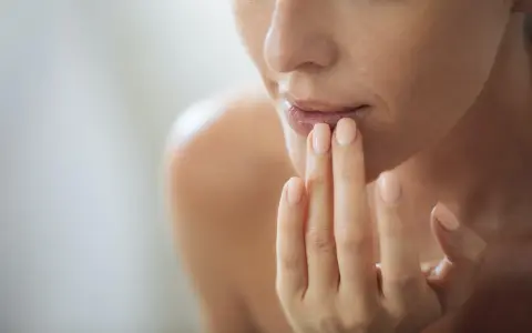 Nahaufnahme einer Frau, die sich mit den Fingern die Lippen berührt. Ein sanfter Blick auf natürliche Schönheit, vielleicht inspiriert von hausmittel gegen falten.