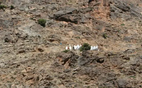 Eine Gruppe von Berber-Algeriern in traditioneller Kleidung wandert auf einem felsigen Hang.