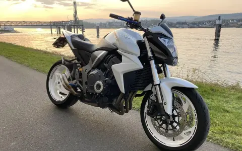 Biały motocykl Honda z silnikiem 35 kw nad rzeką o zachodzie słońca.