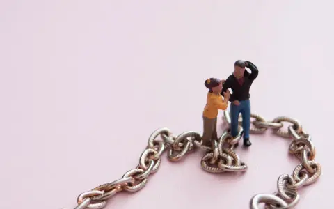 Figuras de pareja unidas por una cadena, simbolizando la codependencia de pareja.
