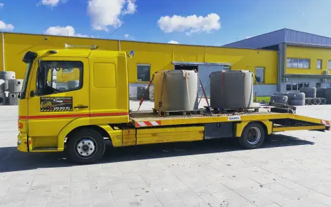 Żółta laweta z dwoma betonowymi elementami, gotowa do transportu. To **assistance warta** uwagi, gdy potrzebujesz przewieźć ciężkie ładunki.