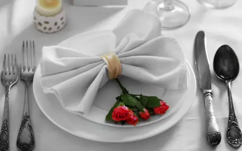 Mesa elegante: tenedor a la izquierda, cuchillo y cuchara a la derecha. Servilleta con rosas, ideal para saber como colocar los cubiertos en la mesa.
