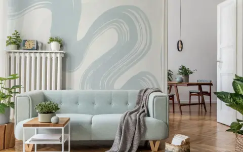Miętowa kanapa i tapeta w stylu baby blue tworzą przytulną atmosferę.