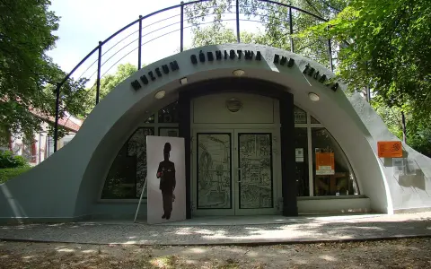Wejście do Muzeum Górnictwa Rud Żelaza. Przed budynkiem stoi wielkoformatowy portret górnika.