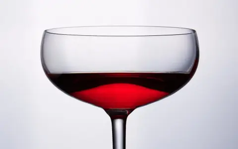 Cachaca co to? Kieliszek z czerwonym, przejrzystym płynem, który może być cachacą, na jasnym tle.