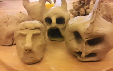 Flera ansikten och figurer i lera, skapade med fantasi. En del ser ut som monster, andra som människor.