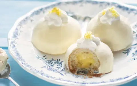 Deliziose tortine al limone, con un ripieno cremoso e una decorazione di panna e scorza di limone.