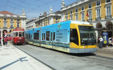 Lizbona tramwaj: nowoczesny, niebiesko-żółty pojazd obok zabytkowego, czerwonego tramwaju na tle żółtych budynków.